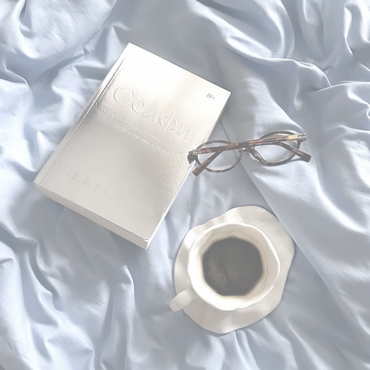 Livro, óculos e café sobre lençol azul